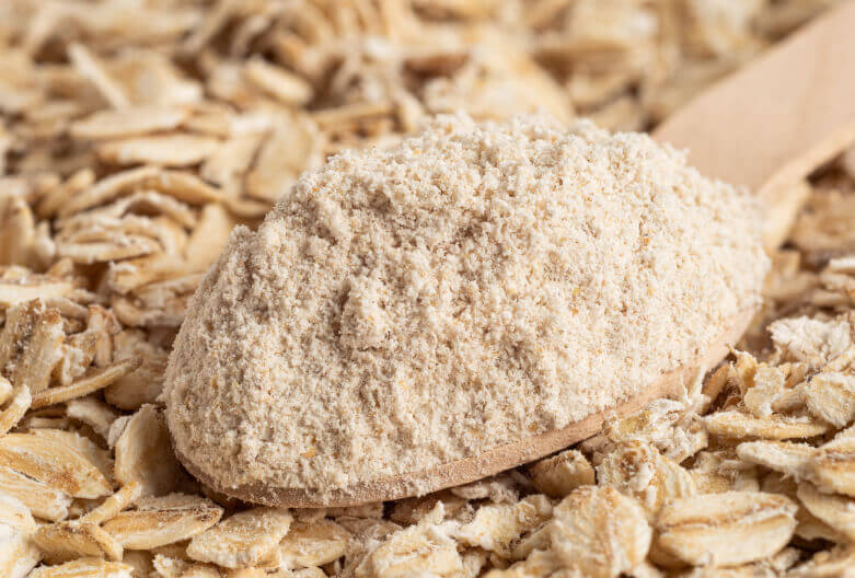 Photo of ground oats on a wooden spoon as an ingredient.