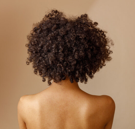 Photo of the back of a woman's head with curly hair.