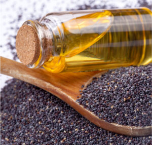 Close up photo of virgin poppy seeds next to a bottle of virgin poppy seed oil.